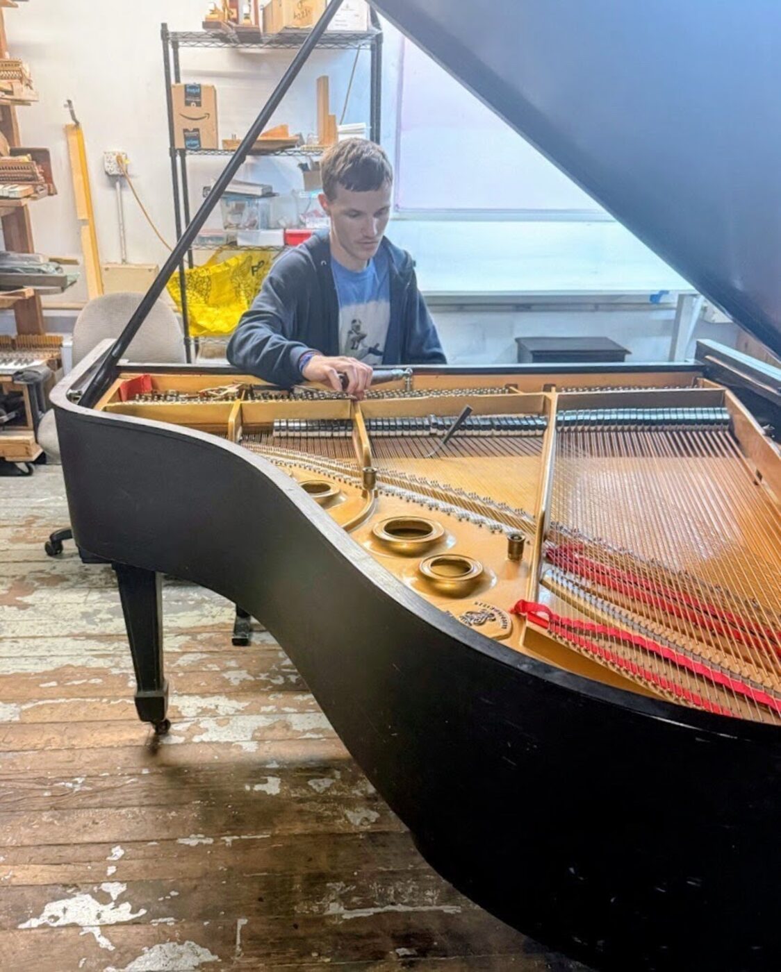 Anthony tuning the strings of a grand piano